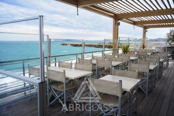 Terrasse en bord de mer protégée par des paravents vitrés