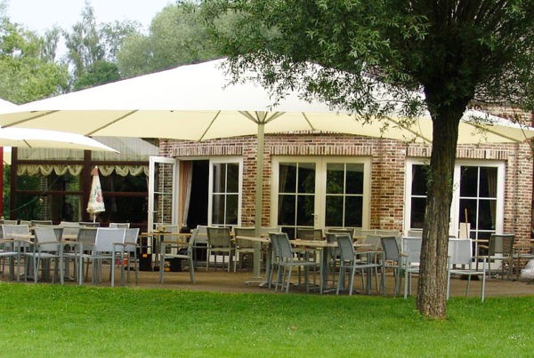 Terrasse ombragée par un parasol Facil rond de couleur claire